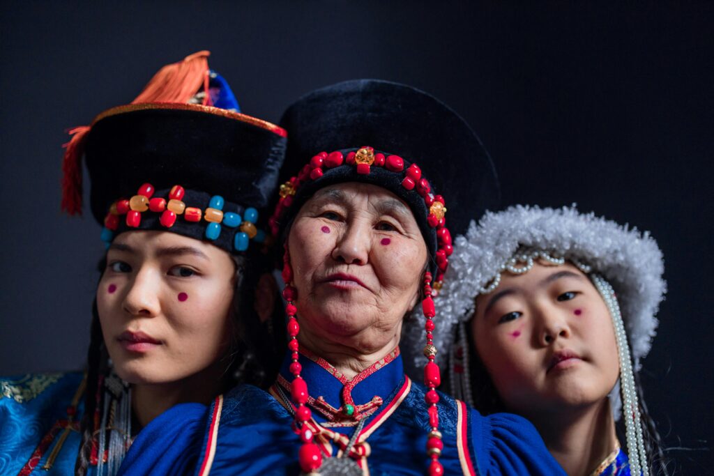 Three Buryat women showcasing traditional attire and cultural heritage in a studio setting.
